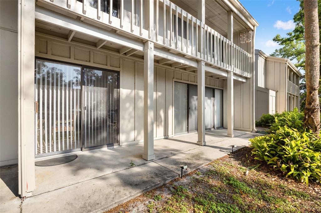 A two-story building exterior features a concrete patio, sliding glass doors, and wooden railings — 2232 BAHIA VISTA STREET UNIT A1, SARASOTA, FL