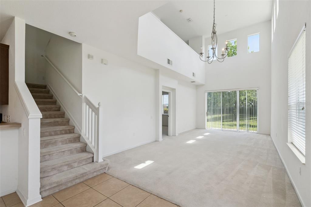 A living room with high ceilings, a staircase, carpeted flooring, and a large chandelier — 1215 SHALLCROSS AVENUE, ORLANDO, FL