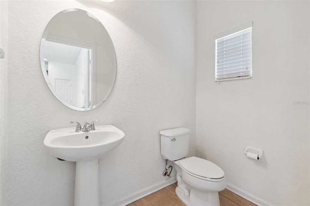 A half bathroom features a pedestal sink, oval mirror, toilet, and a window with blinds — 1215 SHALLCROSS AVENUE, ORLANDO, FL