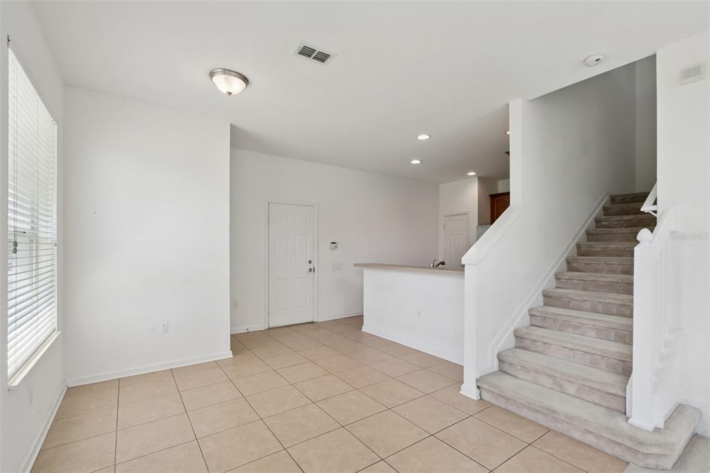 An interior view shows a tiled living area with a staircase and a kitchen counter — 1215 SHALLCROSS AVENUE, ORLANDO, FL