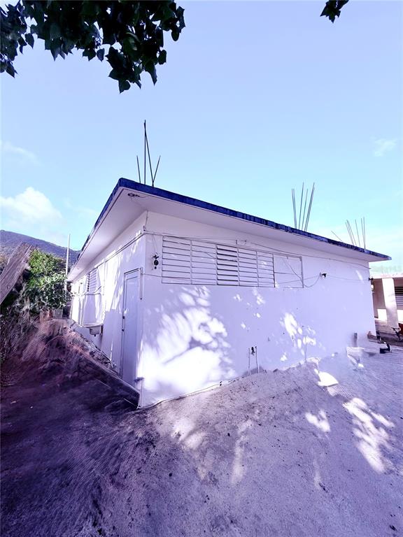 An exterior view of a white, single-story building with louvered windows and exposed roof rebar — 3 ROUTE UNIT KM 114.9, PATILLAS, PR