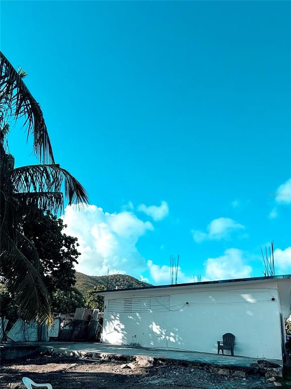 A white, single-story building exterior features a patio area with a chair under a blue sky — 3 ROUTE UNIT KM 114.9, PATILLAS, PR