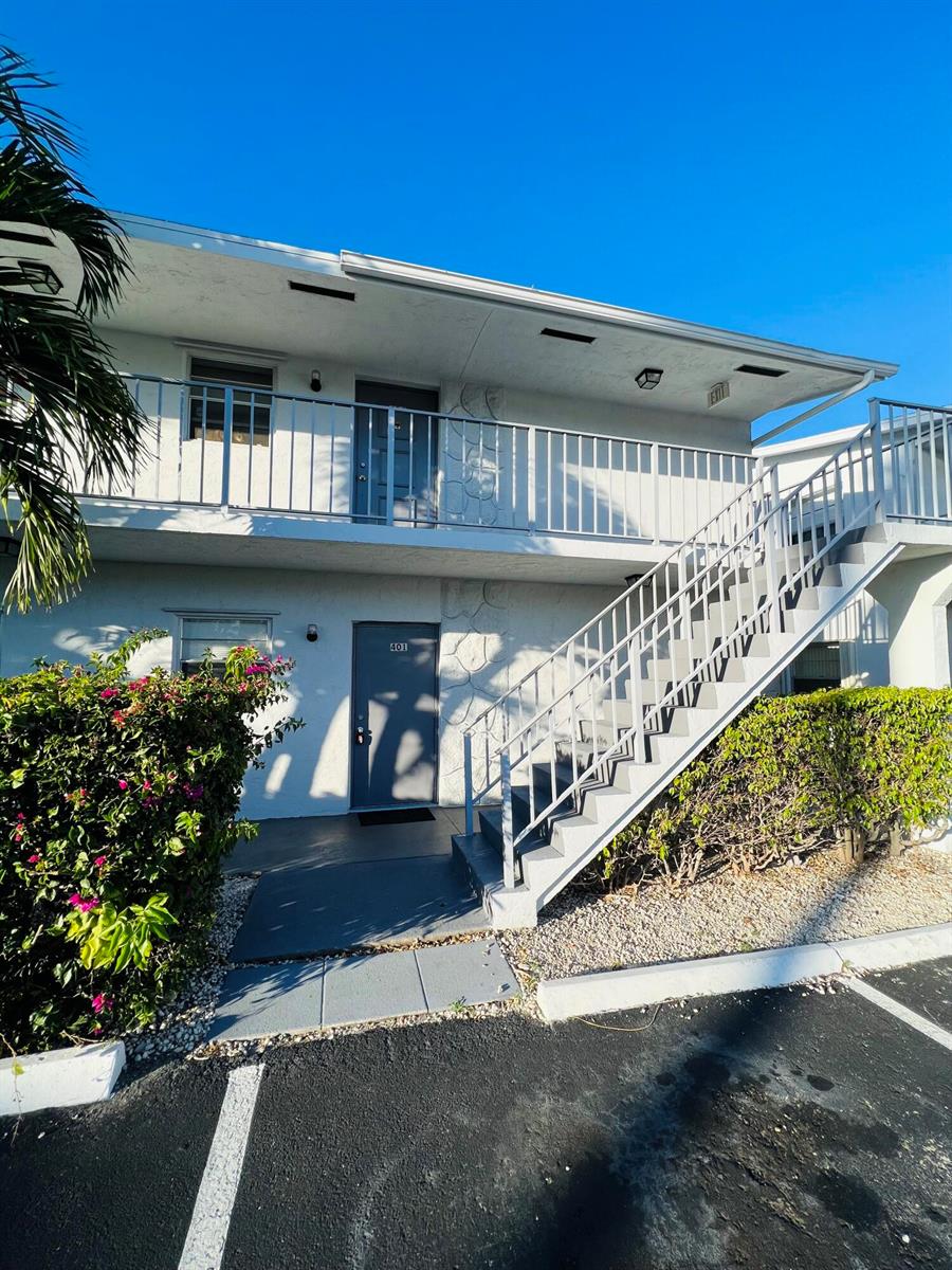 A two-story apartment building exterior features a gray door labeled 401 and metal stairs — 510 24th Avenue N # 401, FL 33460, FL