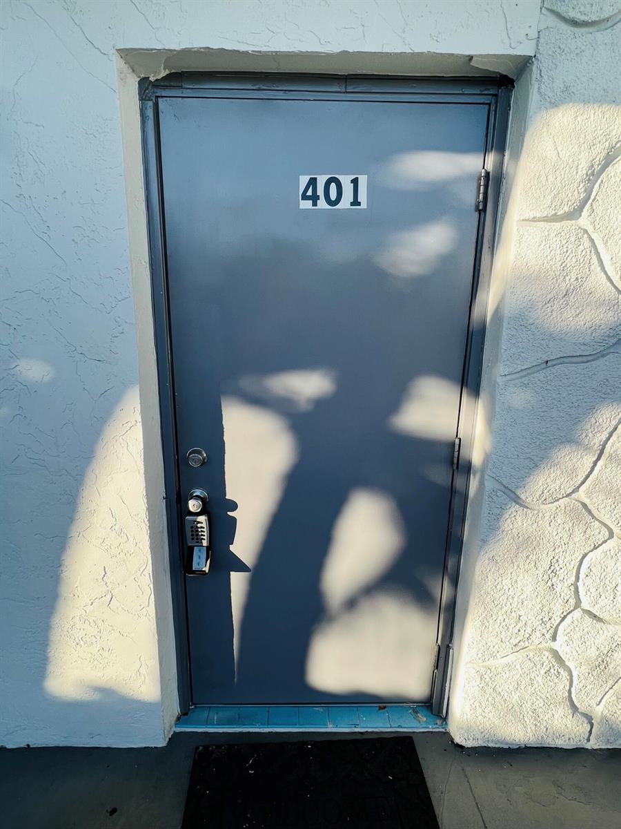 A gray metal door labeled 401 with a keypad lock set in a textured wall — 510 24th Avenue N # 401, FL 33460, FL