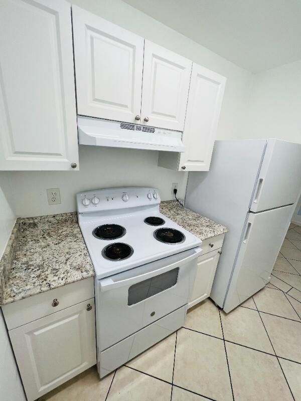 A kitchen features white cabinets, granite countertops, a white stove, and a white refrigerator — 510 24th Avenue N # 401, FL 33460, FL