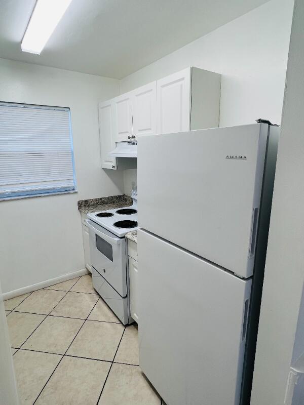 A small kitchen features white cabinets, a white refrigerator, an electric stove, and tiled floors — 510 24th Avenue N # 401, FL 33460, FL