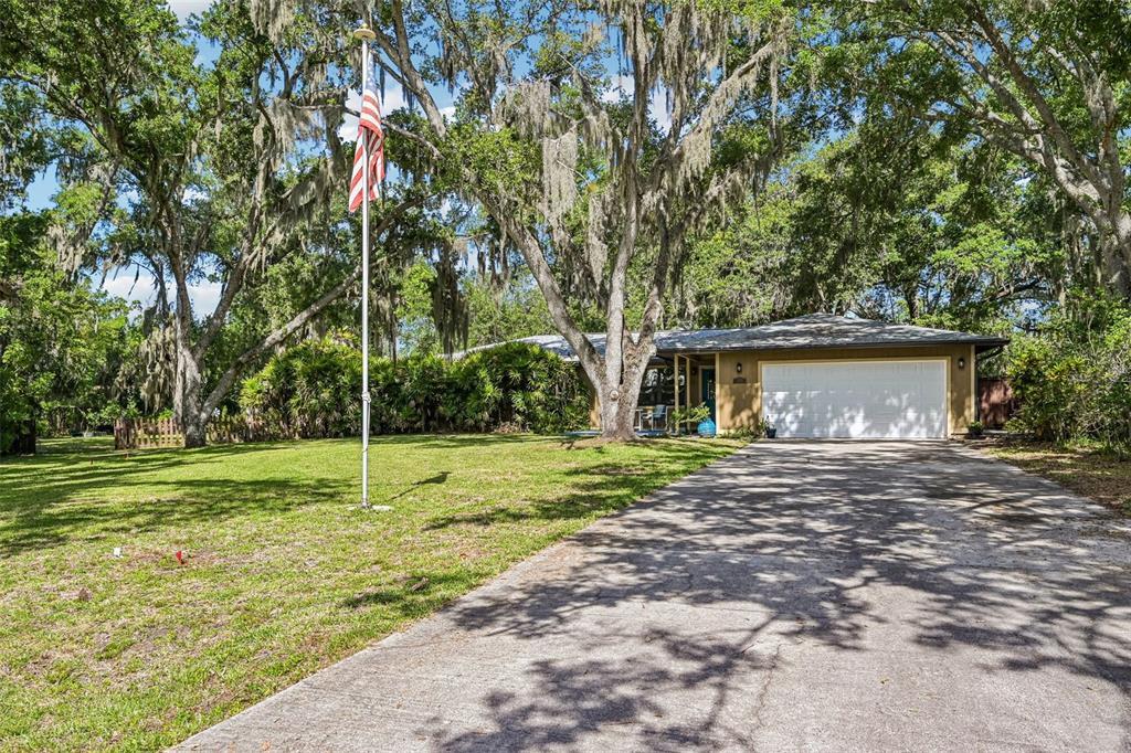 A single-story house with a two-car garage, a flagpole, and large trees in the yard — 3304 SWAAN LANE, SARASOTA, FL