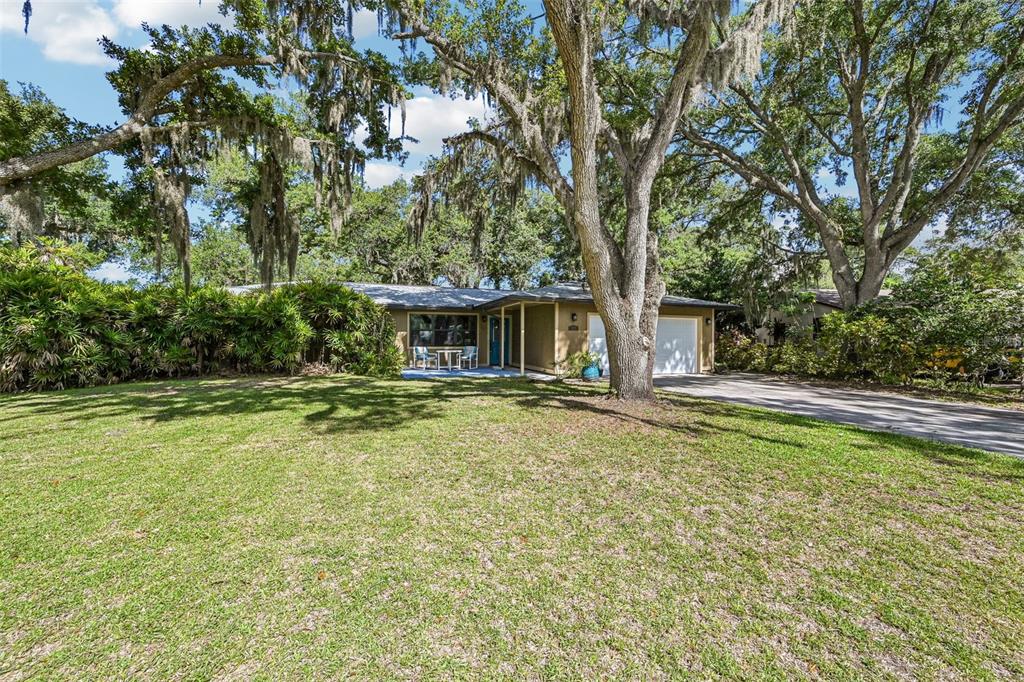A single-story house with a two-car garage sits behind a large lawn and mature trees — 3304 SWAAN LANE, SARASOTA, FL
