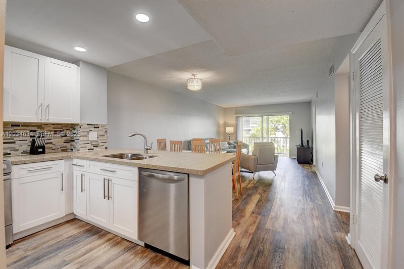 A kitchen with white cabinets and stainless steel appliances opens into a living area — 9880 Marina Blvd # 1516, Boca Raton FL 33428, BOCA RATON, FL