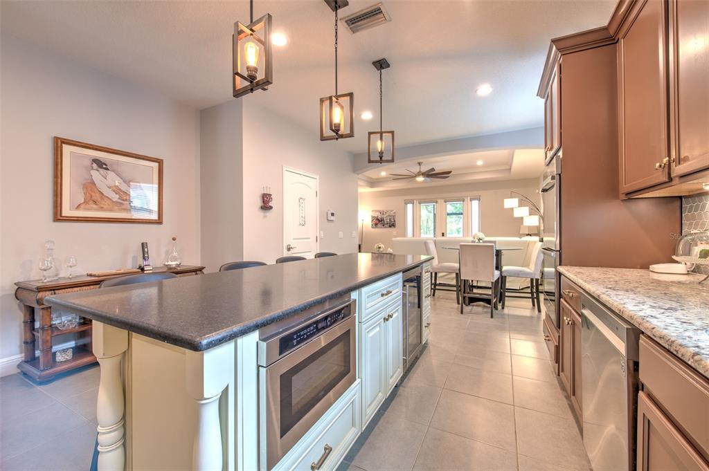 A kitchen with a dark island, light cabinets, granite countertops, and pendant lighting — 842 VINO VERDE CIRCLE, BRANDON, FL