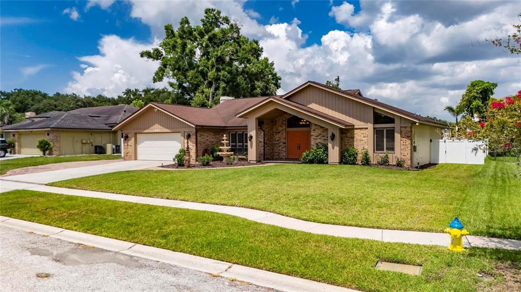 A single-story brick and wood-sided house features a front lawn, driveway, and a fire hydrant — 2001 CIMMARON RUN DRIVE, VALRICO, FL