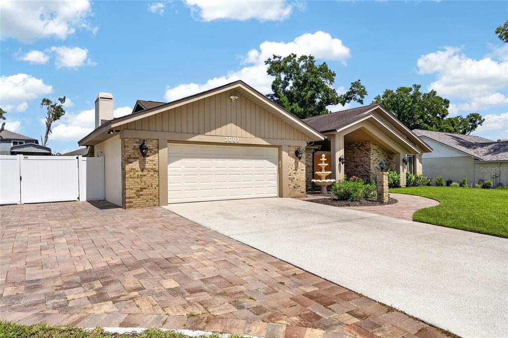 A tan house with a brick facade, a two-car garage, and a paved driveway — 2001 CIMMARON RUN DRIVE, VALRICO, FL