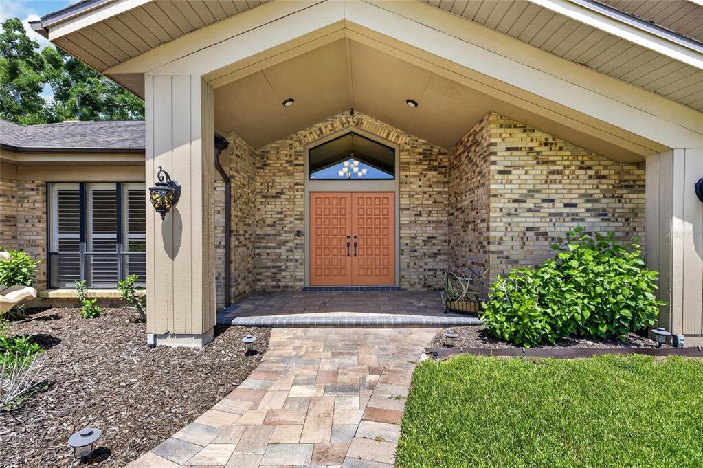 A brick house exterior features a covered entryway with double doors and a stone walkway — 2001 CIMMARON RUN DRIVE, VALRICO, FL