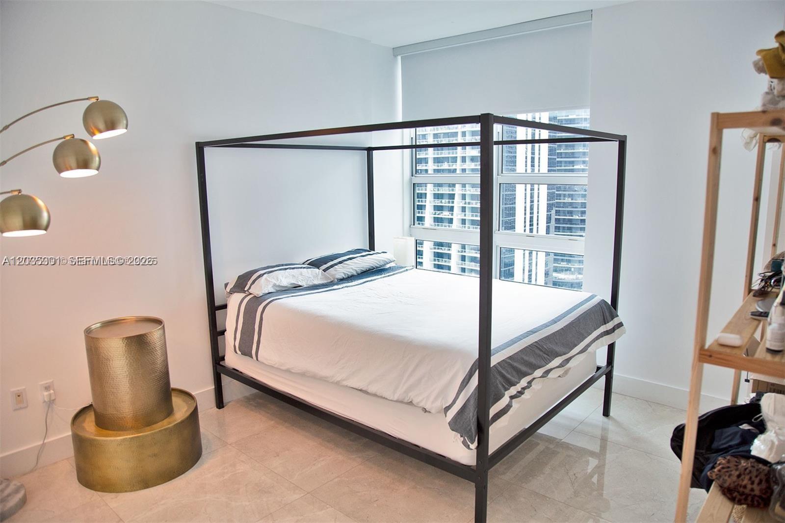 A bedroom features a black metal canopy bed, gold side tables, and a city view — 951 Brickell Ave # 3007, Miami FL 33131, MIAMI, FL