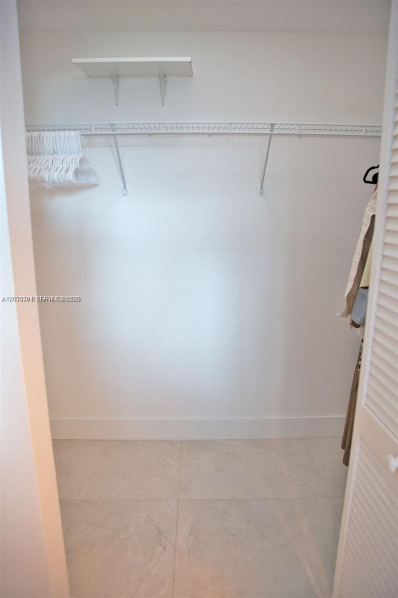 A closet features white wire shelving, a small upper shelf, and light-colored tile flooring — 951 Brickell Ave # 3007, Miami FL 33131, MIAMI, FL