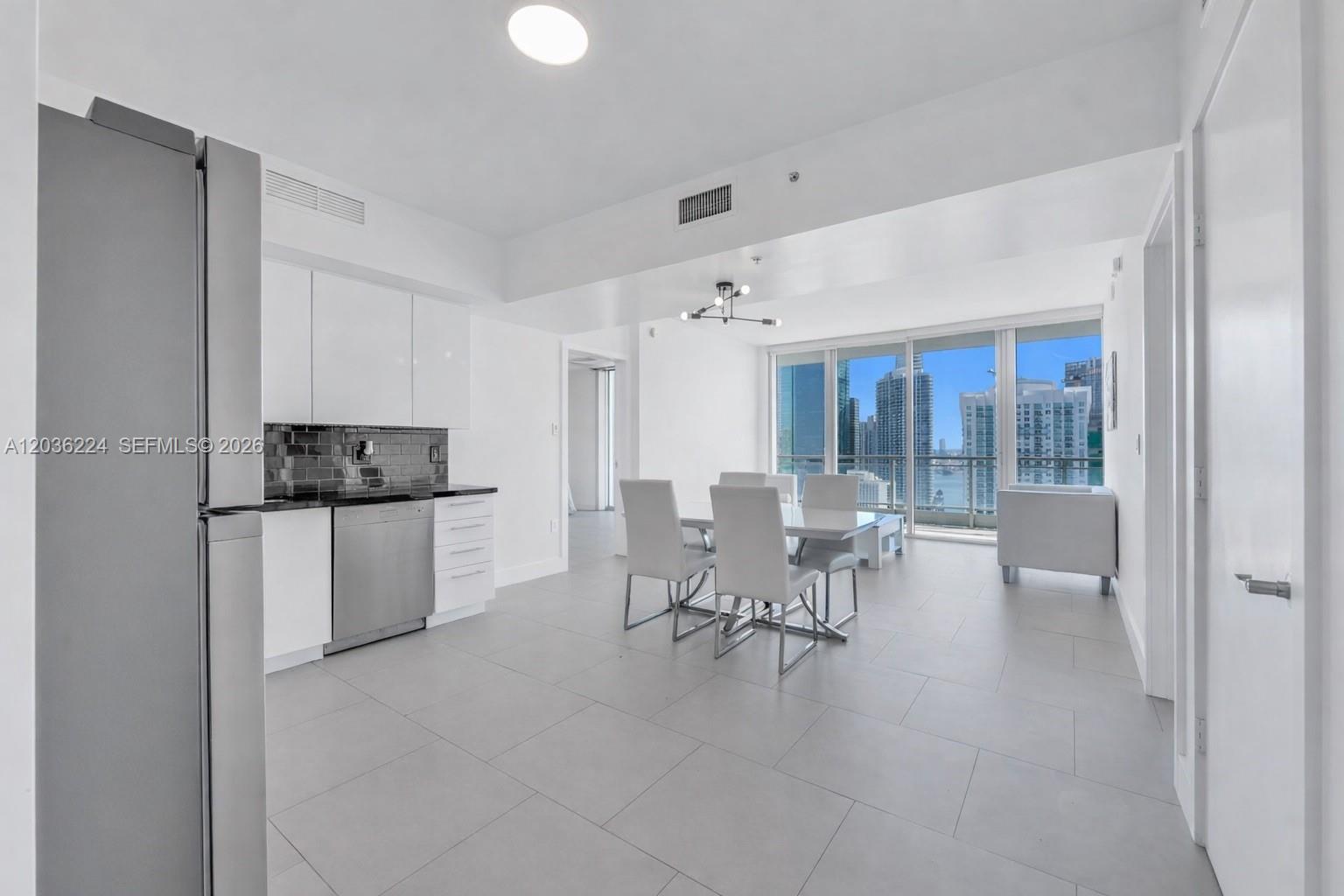 A modern kitchen and dining area feature white cabinetry, stainless steel appliances, and city views — 92 SW 3rd St # 3611, Miami FL 33130, MIAMI, FL