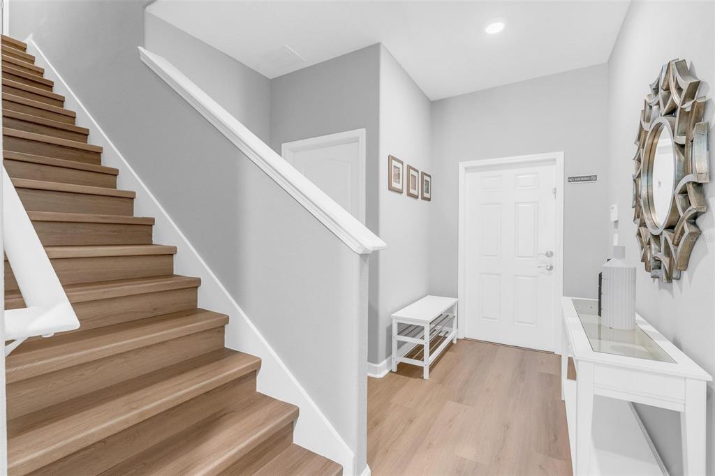 An entryway features light wood flooring, a staircase with wooden steps, and a white console table — 2903 BANANA PALM DRIVE, KISSIMMEE, FL