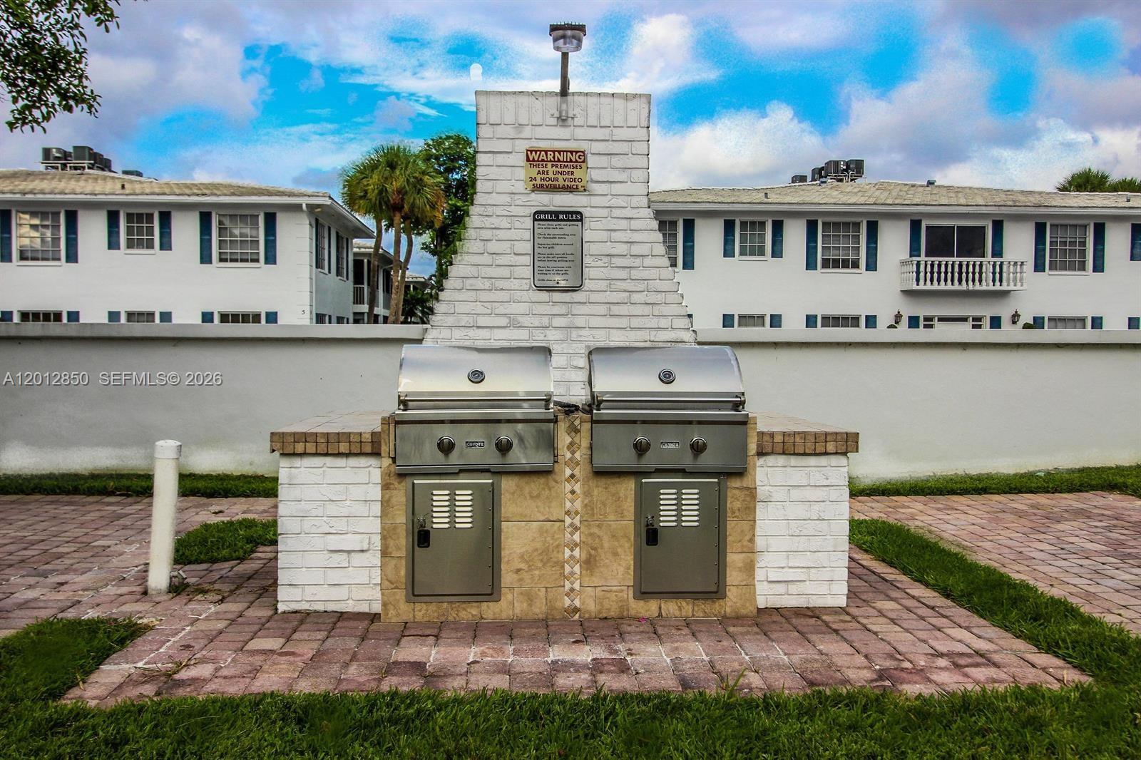 An outdoor grilling station with two stainless steel grills built into a white brick structure — FORT LAUDERDALE, FL