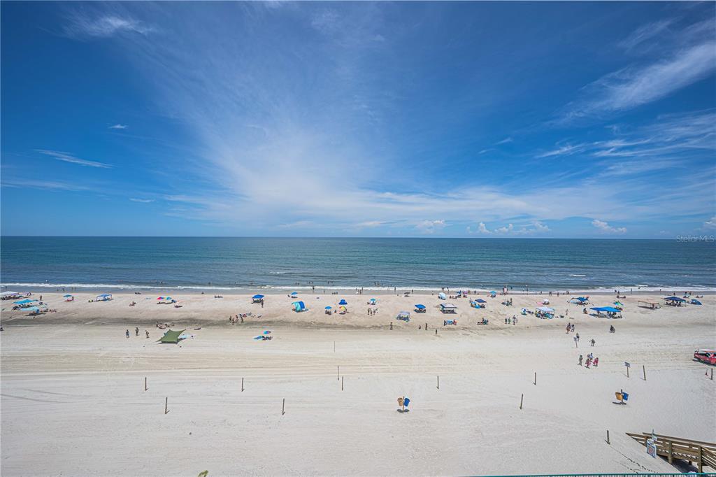An elevated view of a sandy beach with people, umbrellas, and the ocean under blue skies — 4575 S ATLANTIC AVENUE UNIT 6607, PONCE INLET, FL