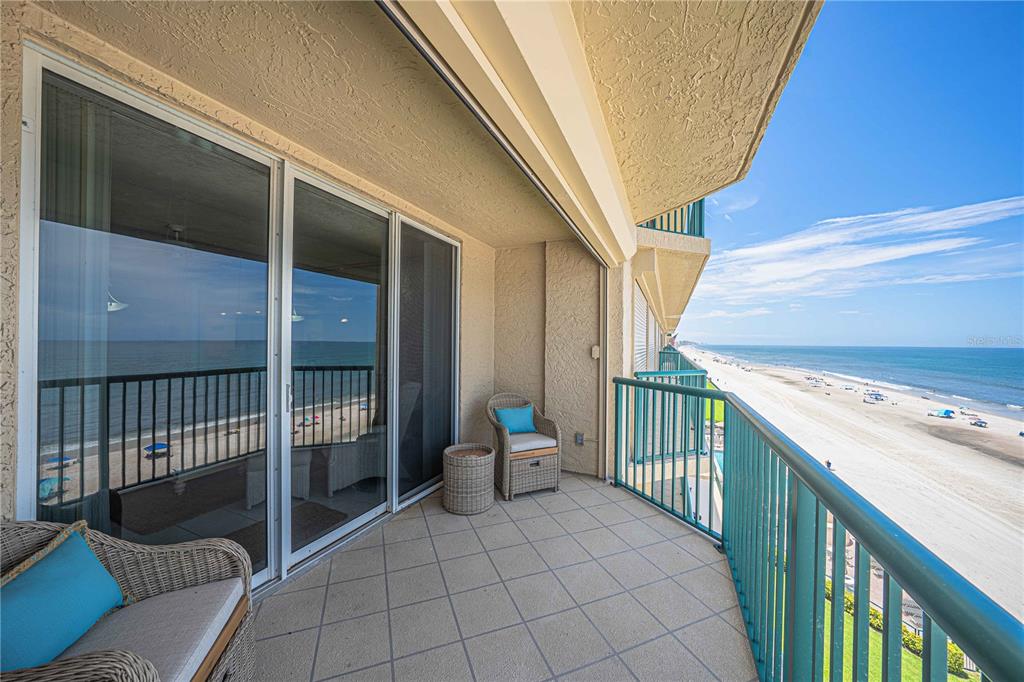 A balcony with wicker furniture overlooks a sandy beach and the ocean — 4575 S ATLANTIC AVENUE UNIT 6607, PONCE INLET, FL