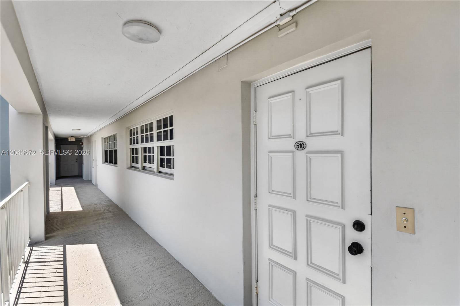 An exterior apartment hallway features a white door labeled 510 and a windowed wall — 3010 N Course Dr # 510, Pompano Beach FL 33069, POMPANO BEACH, FL