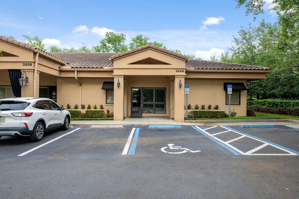 A tan commercial building exterior features a central entrance and designated handicap parking spaces — 2666 MAGUIRE ROAD, OCOEE, FL