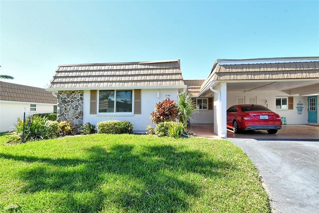 A single-story house with a stone facade, a front lawn, and a covered carport — 2607 RIVERBLUFF PARKWAY UNIT V145, SARASOTA, FL