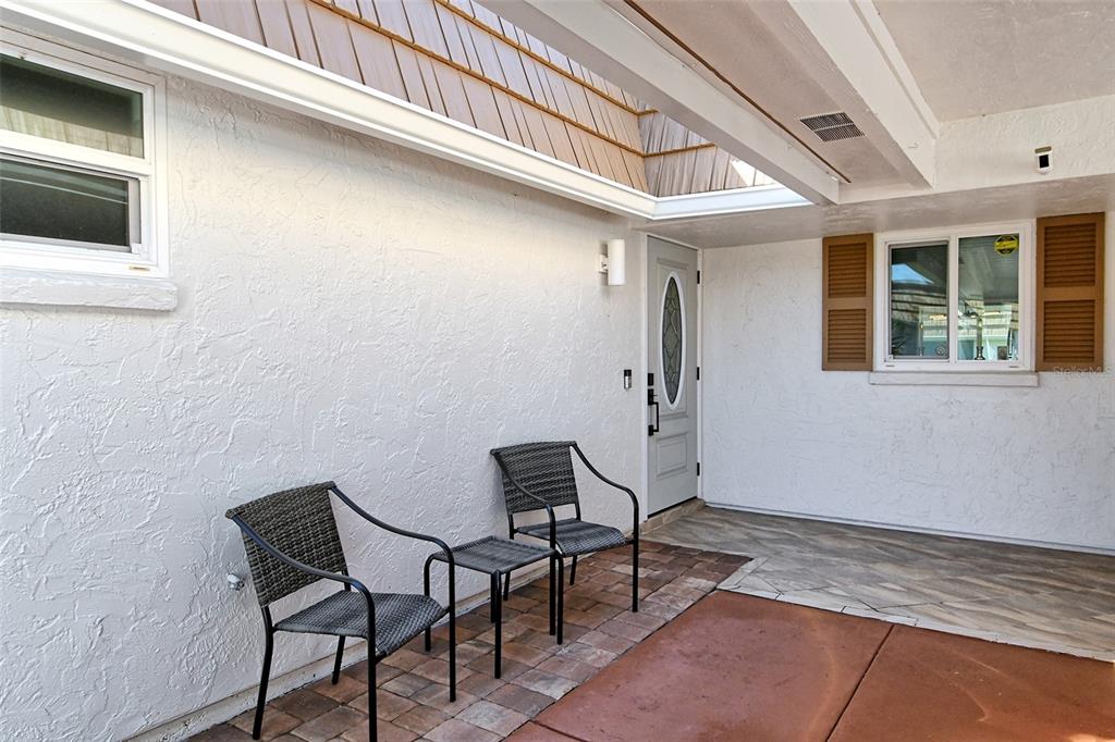 A covered patio features two wicker chairs, a small table, and a light gray door — 2607 RIVERBLUFF PARKWAY UNIT V145, SARASOTA, FL