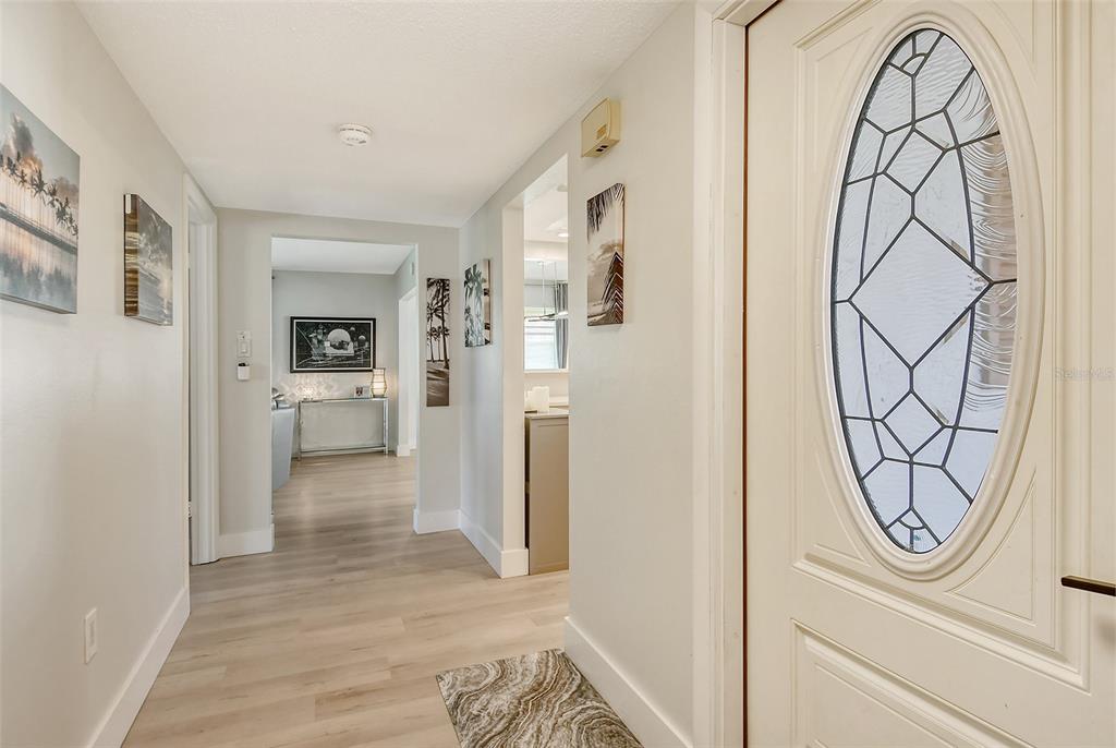 An entryway with light wood-look flooring, white walls, and a door with an oval glass insert — 2607 RIVERBLUFF PARKWAY UNIT V145, SARASOTA, FL