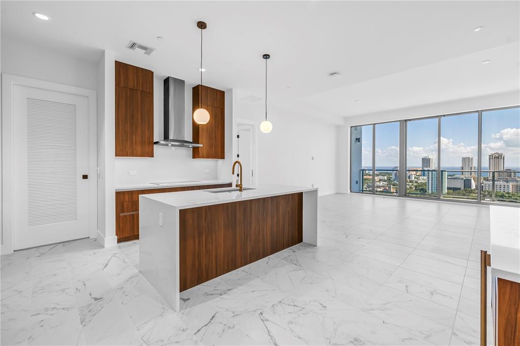 A modern kitchen features wood cabinets, a white waterfall island, and floor-to-ceiling windows with views — 777 3RD AVENUE N UNIT 1704, ST PETERSBURG, FL