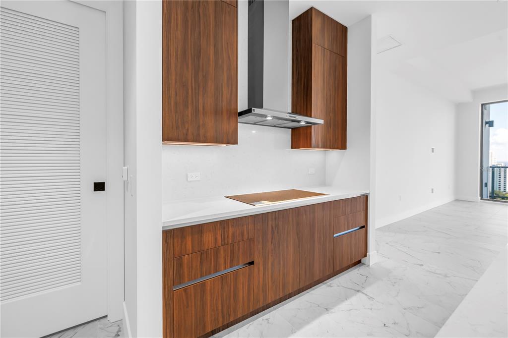 A modern kitchen features wood-grain cabinets, a stainless steel range hood, and white marble flooring — 777 3RD AVENUE N UNIT 1704, ST PETERSBURG, FL