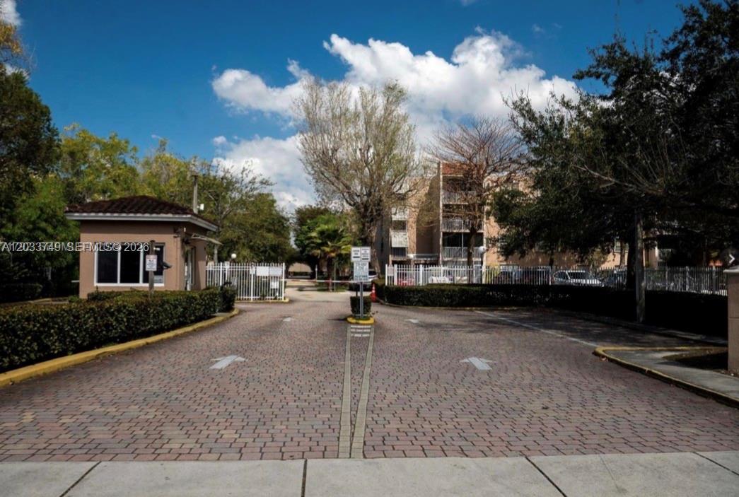 A gated entrance with a guardhouse leads into a residential complex with paved roads — 8421 NW 8th St # 203, Miami FL 33126, MIAMI, FL