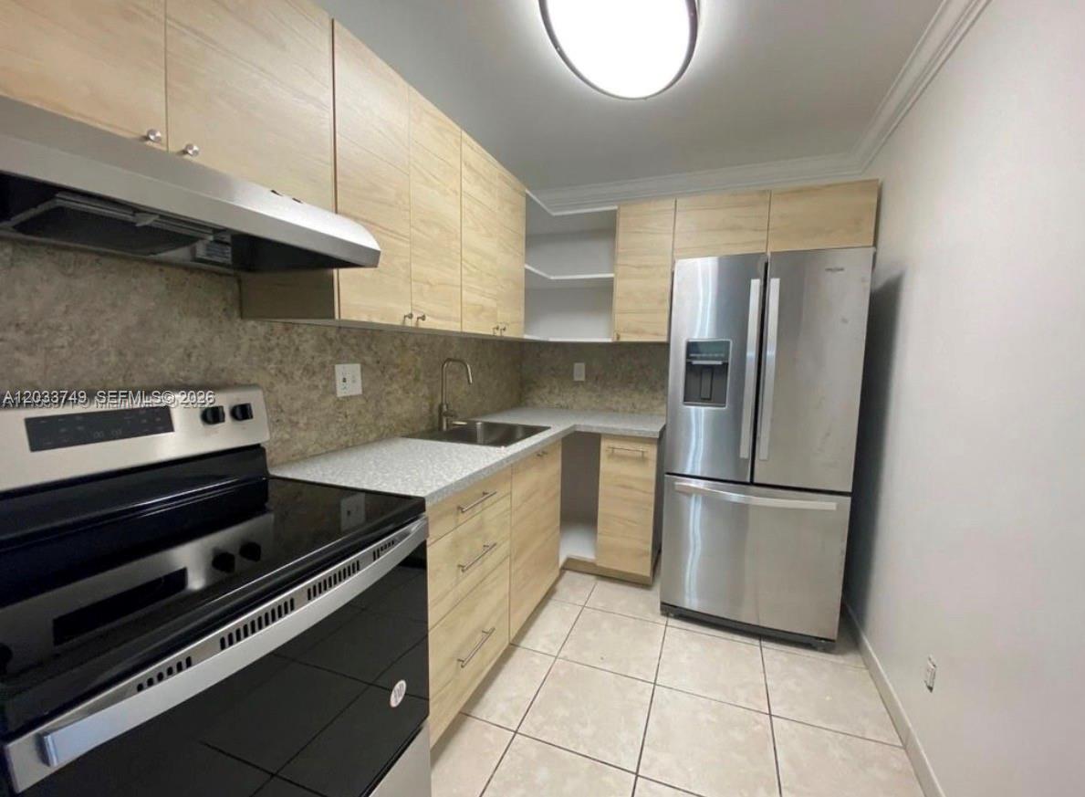 A kitchen features light wood cabinets, stainless steel appliances, and a speckled countertop — 8421 NW 8th St # 203, Miami FL 33126, MIAMI, FL