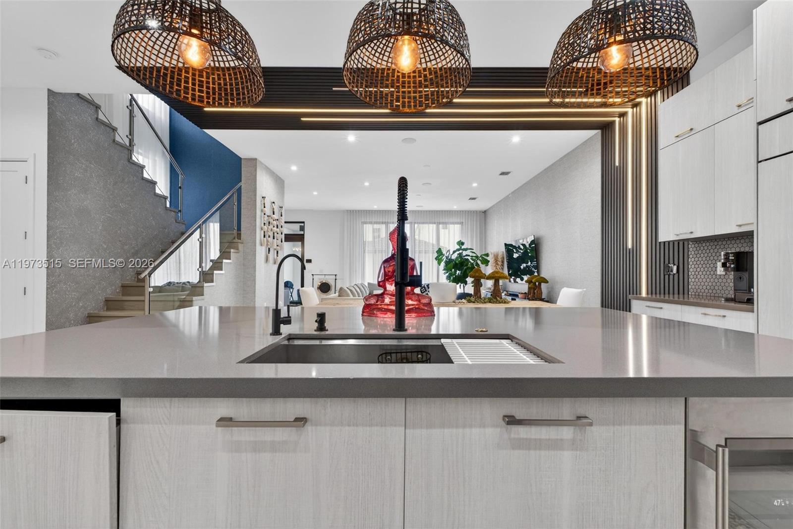 A modern kitchen island with a sink overlooks an open-concept living area with stairs — 8126 NW 48th Ter, Doral FL 33166, DORAL, FL