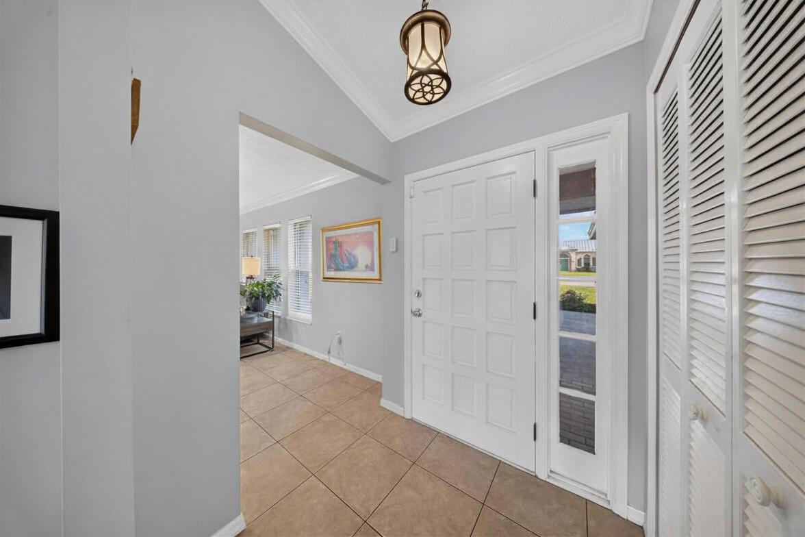 An entryway features light gray walls, tiled flooring, a white front door, and a pendant light — 4800 Eagle Drive, Fort Pierce FL 34951, FORT PIERCE, FL