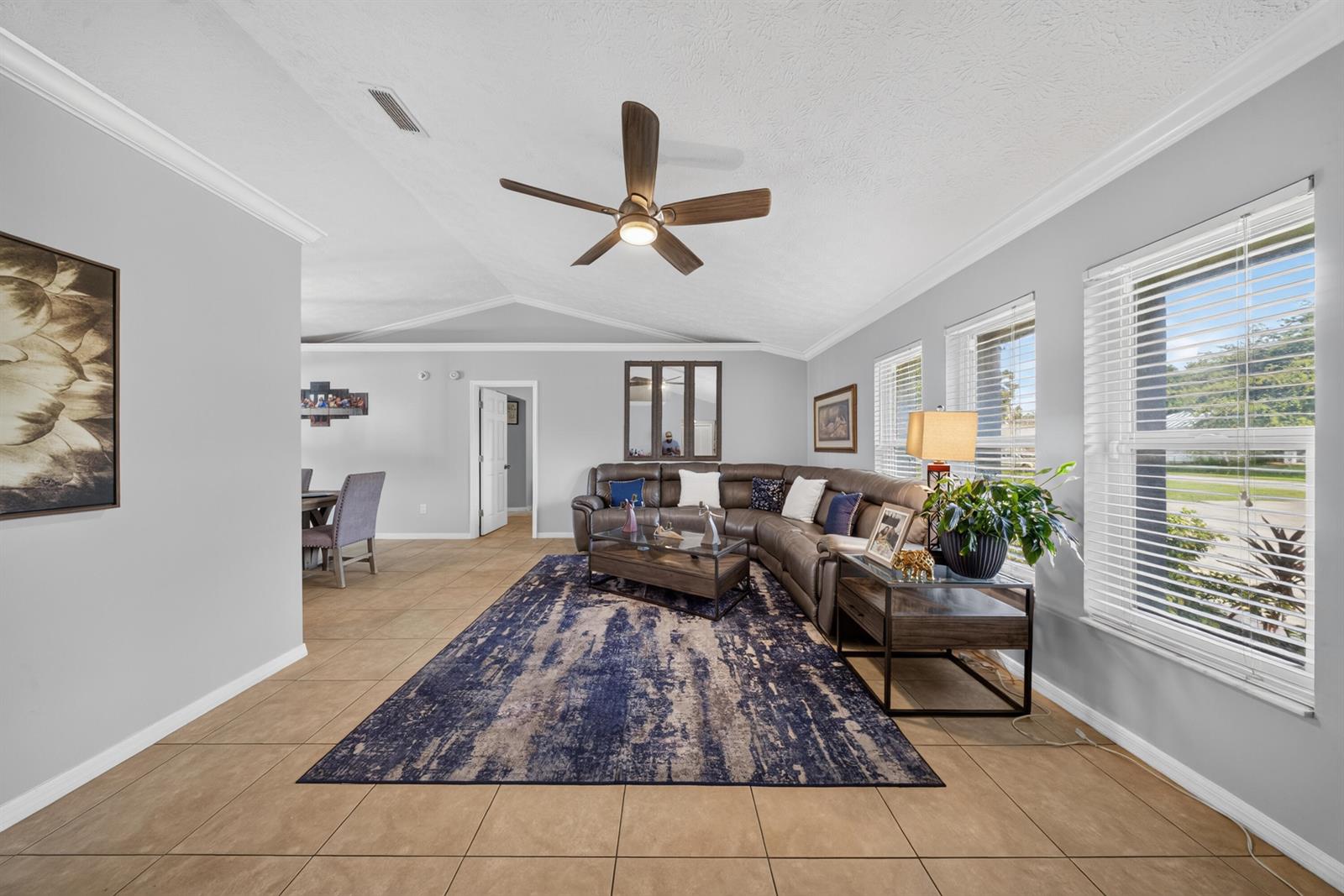 A living room features a large sectional sofa, a blue area rug, and tile flooring — 4800 Eagle Drive, Fort Pierce FL 34951, FORT PIERCE, FL