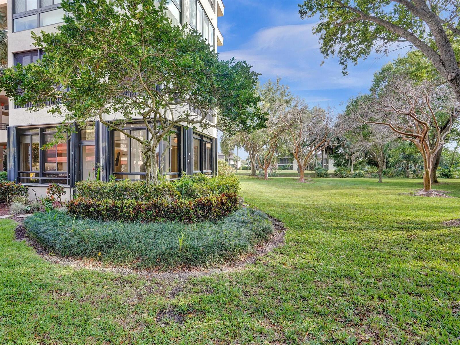 A multi-story building exterior with large windows overlooks a grassy lawn and several trees — 7546 La Paz Boulevard # 108, Boca Raton FL 33433, BOCA RATON, FL