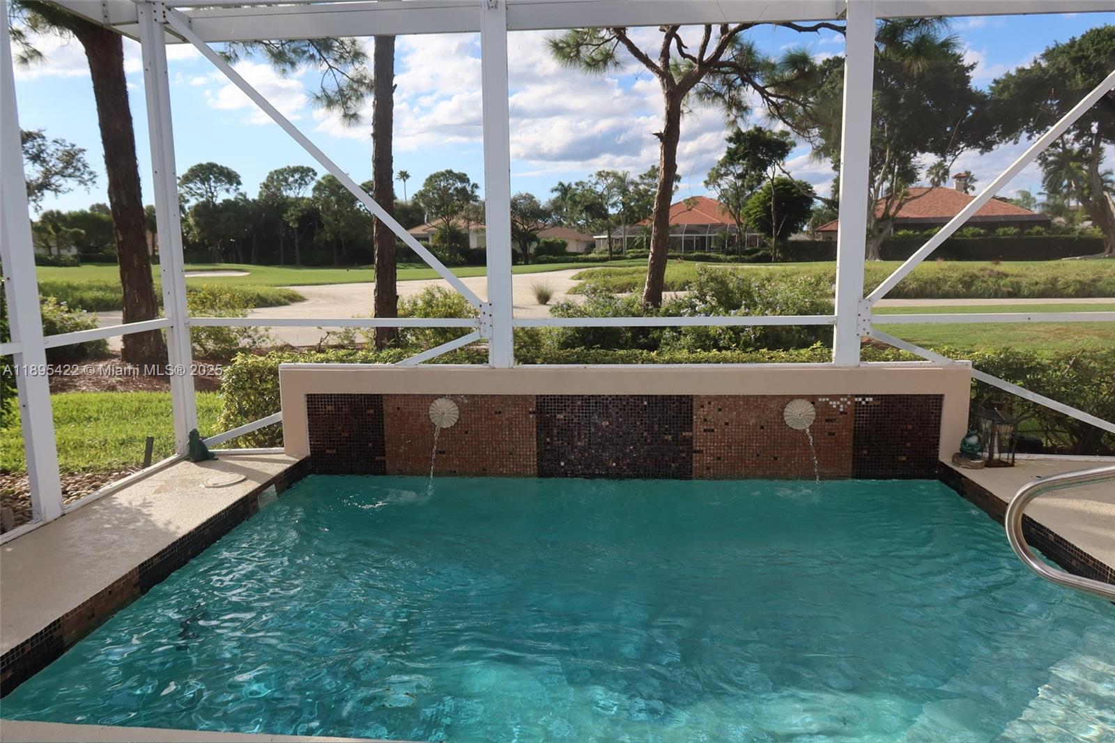 A small pool with two water fountains sits inside a screened-in patio overlooking a golf course — 8189 Sandpiper Way, West Palm Beach FL 33412, WEST PALM BEACH, FL