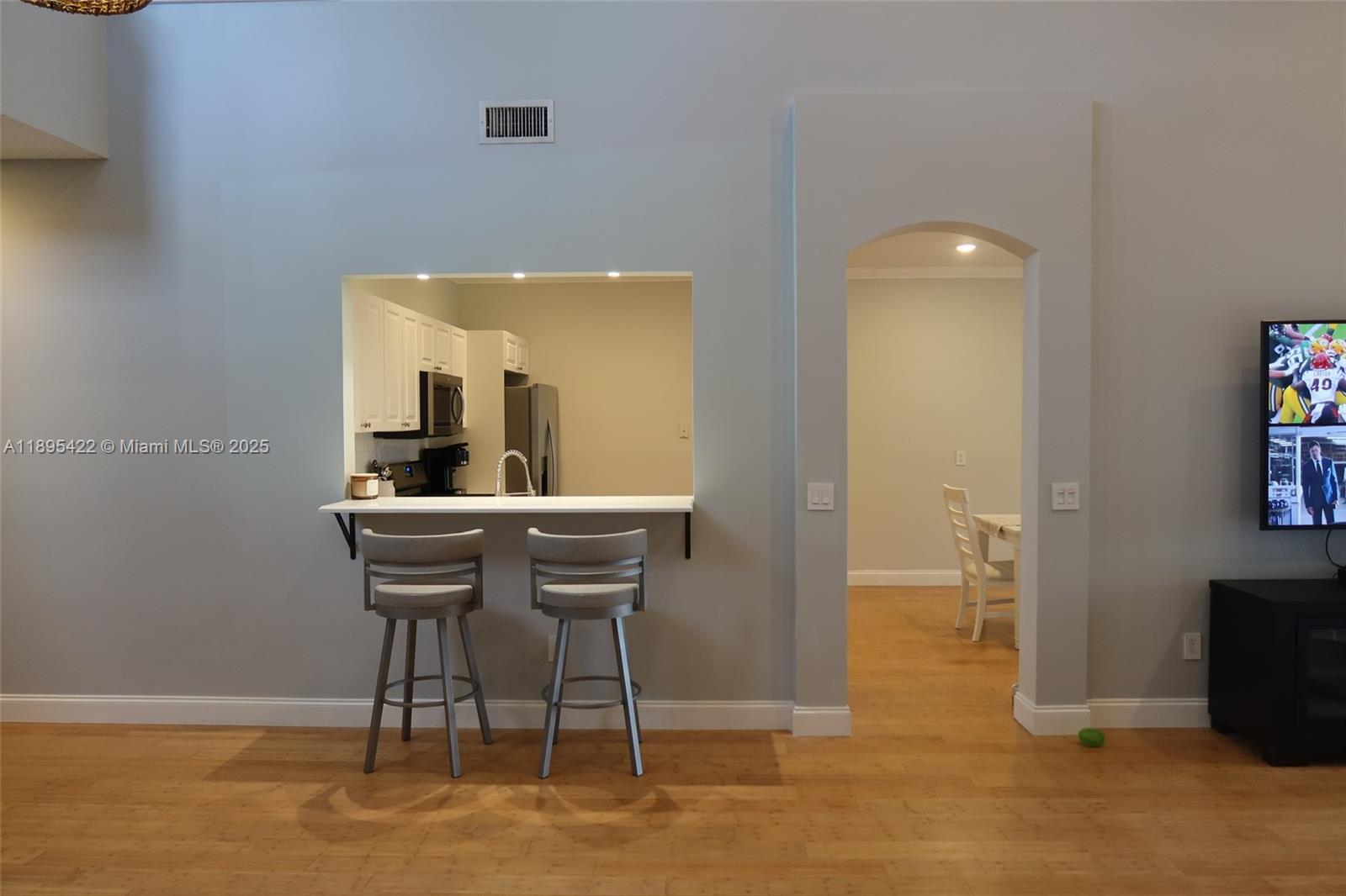 A kitchen pass-through window with a breakfast bar sits beside an arched doorway — 8189 Sandpiper Way, West Palm Beach FL 33412, WEST PALM BEACH, FL