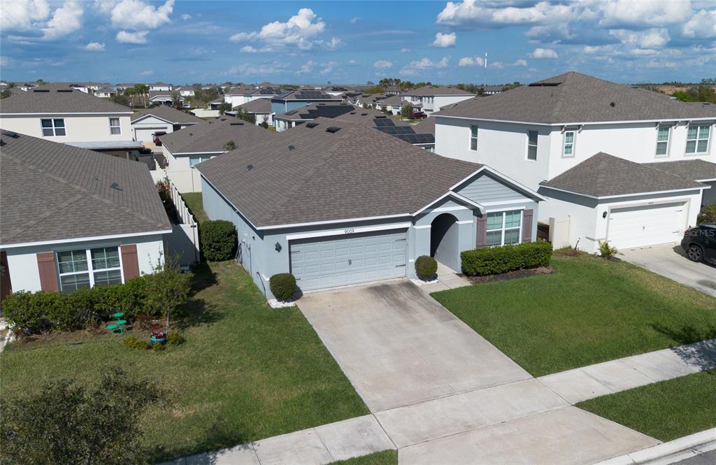 An aerial view shows a single-story suburban house with a gray exterior and shingled roof — 9009 PINALES WAY, KISSIMMEE, FL
