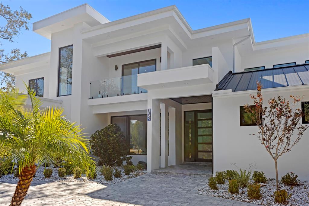 A modern two-story white house with a glass balcony, metal roof, and paved driveway — 2089 ARLINGTON STREET, SARASOTA, FL