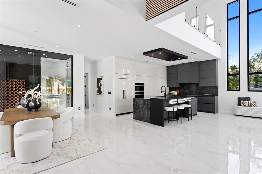 A modern open-concept kitchen and dining area features white marble floors and dark cabinetry — 2089 ARLINGTON STREET, SARASOTA, FL