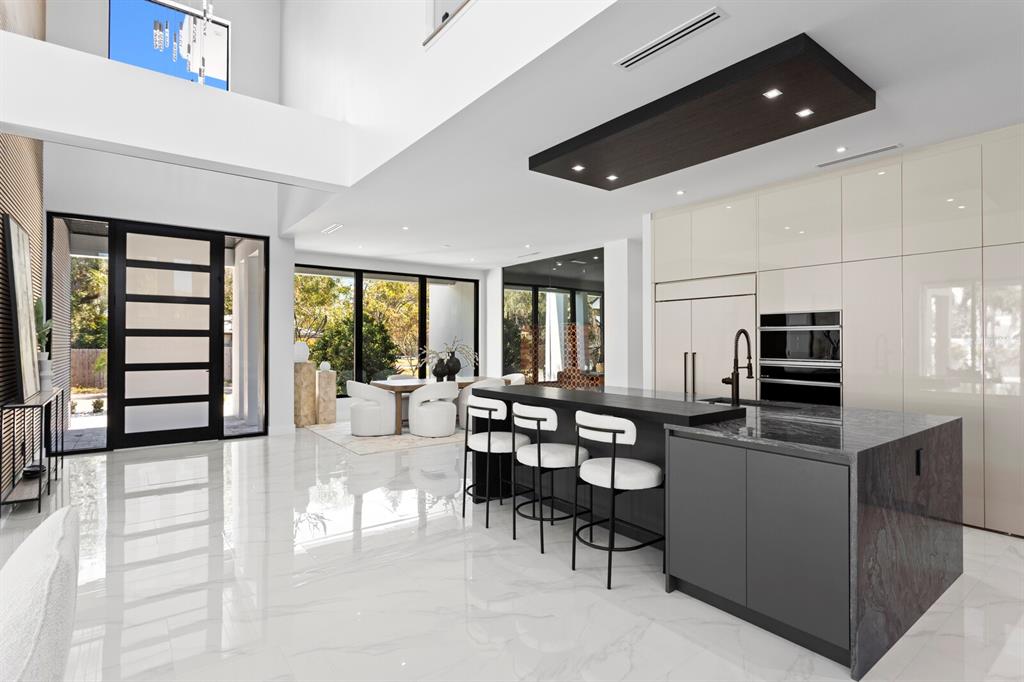 A modern open-concept kitchen and dining area features white marble floors and dark cabinetry — 2089 ARLINGTON STREET, SARASOTA, FL