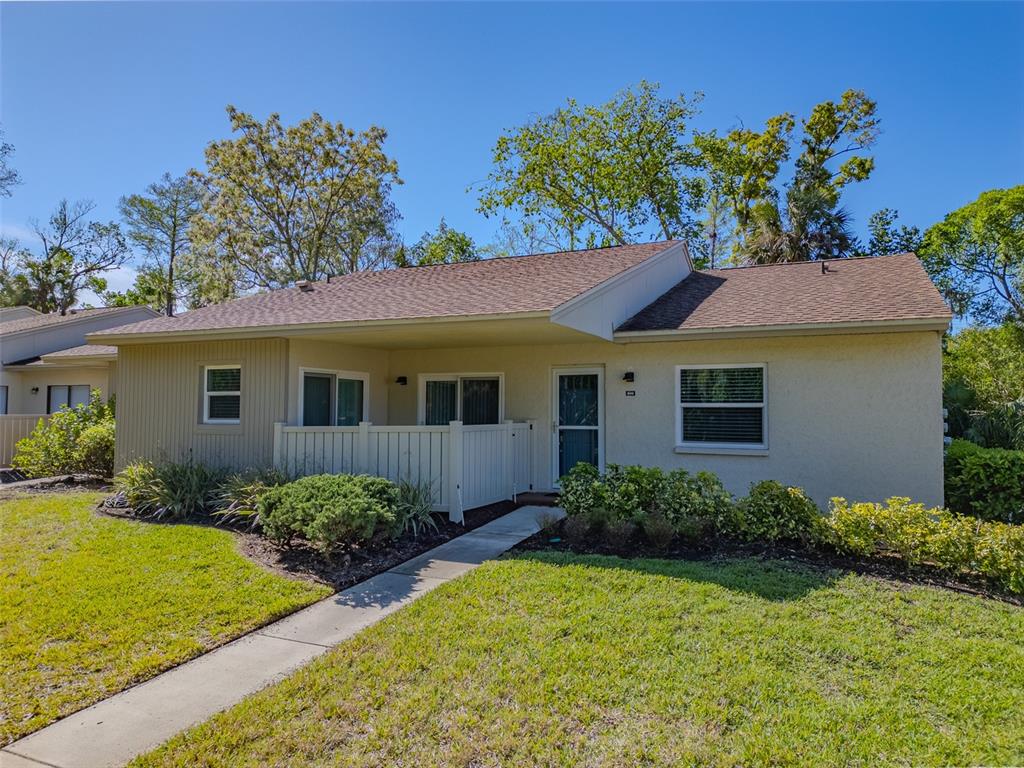 A single-story house with a tan stucco exterior, a small front patio, and a walkway — 600 S WOODLANDS DRIVE, OLDSMAR, FL