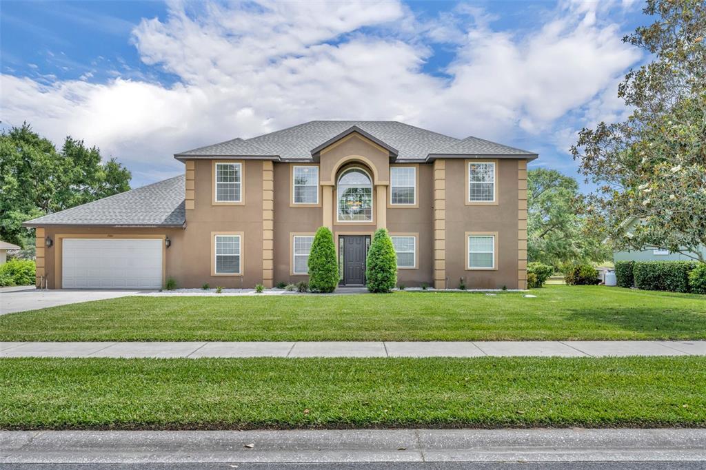 A two-story brown house with a garage, arched entryway, and a large front lawn — 15001 GREEN VALLEY BOULEVARD, CLERMONT, FL