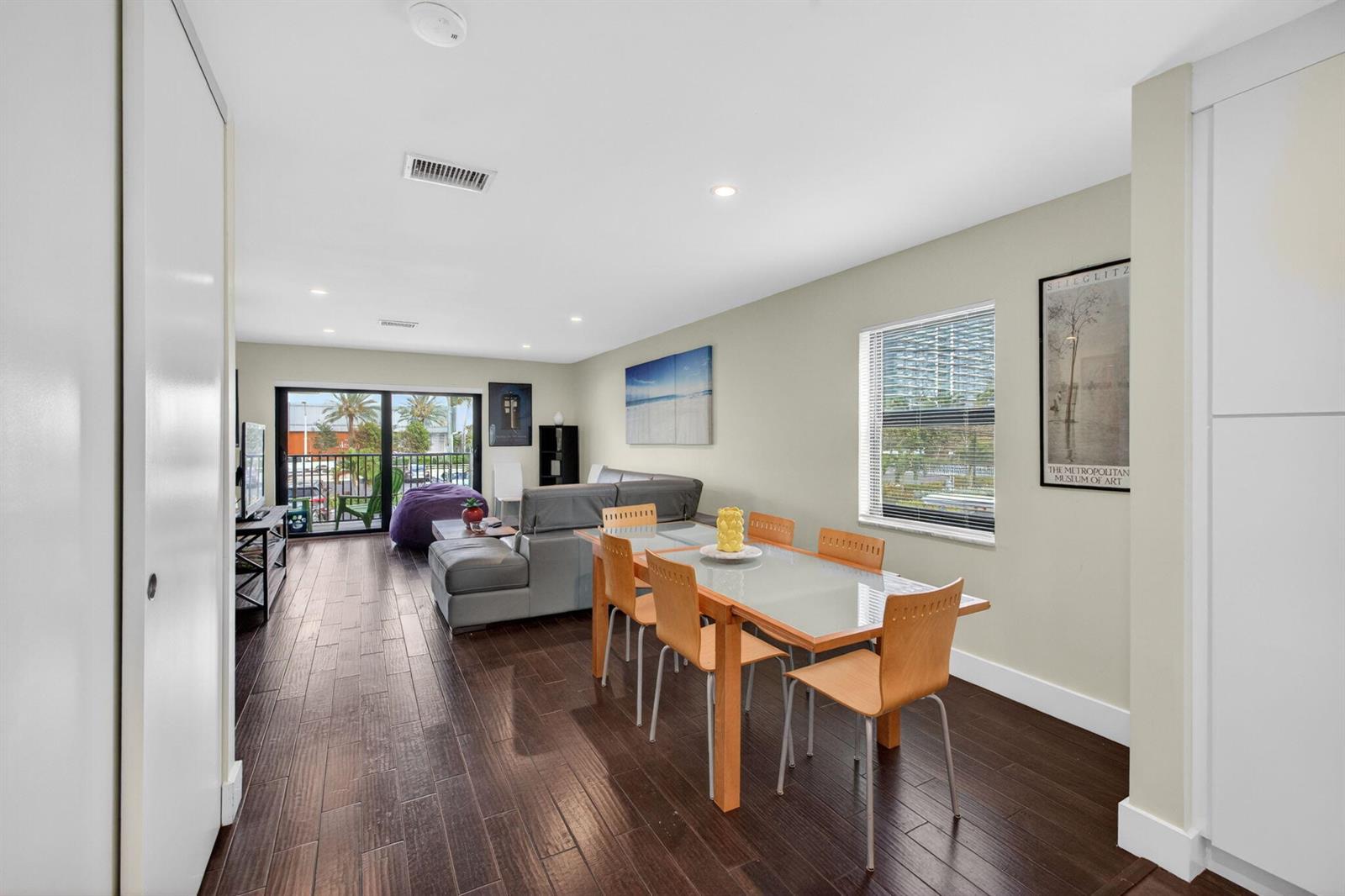 A living and dining area with dark wood floors, a glass table, and a balcony — 3250 NE 12th Street NE # 6, Pompano Beach FL 33062, POMPANO BEACH, FL