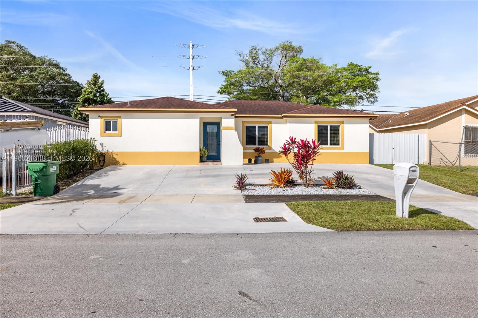 A single-story house with a white and yellow exterior features a concrete driveway and landscaping — 20814 SW 126th Ct, Miami FL 33177, MIAMI, FL