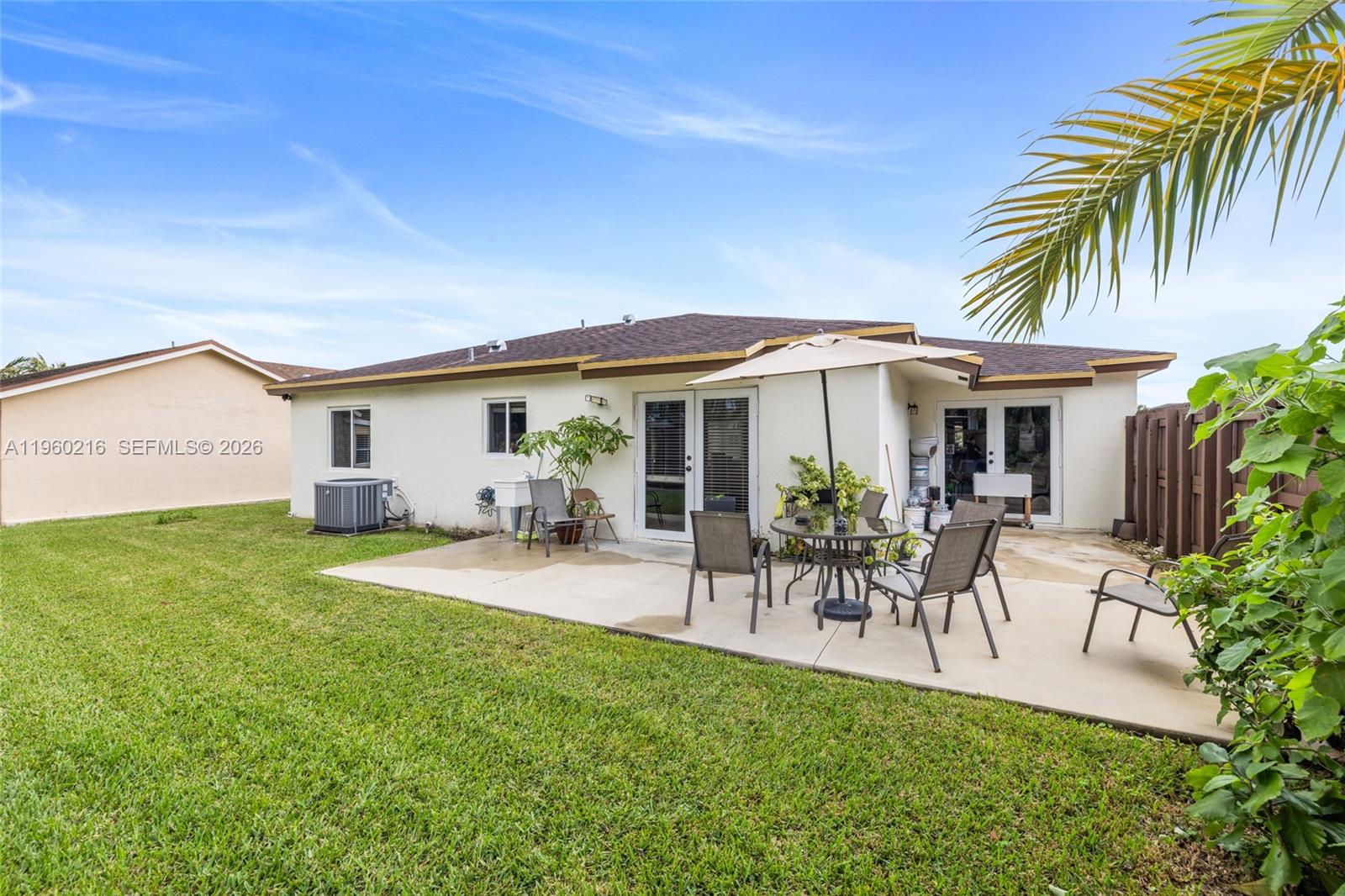 A backyard features a concrete patio with outdoor furniture, a lawn, and a house exterior — 20814 SW 126th Ct, Miami FL 33177, MIAMI, FL