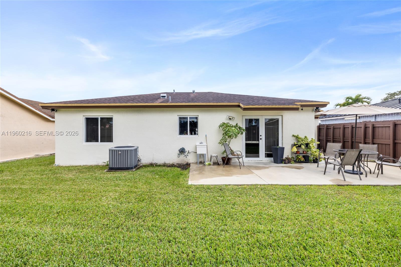 The exterior view shows a house with a concrete patio, lawn, and backyard fencing — 20814 SW 126th Ct, Miami FL 33177, MIAMI, FL