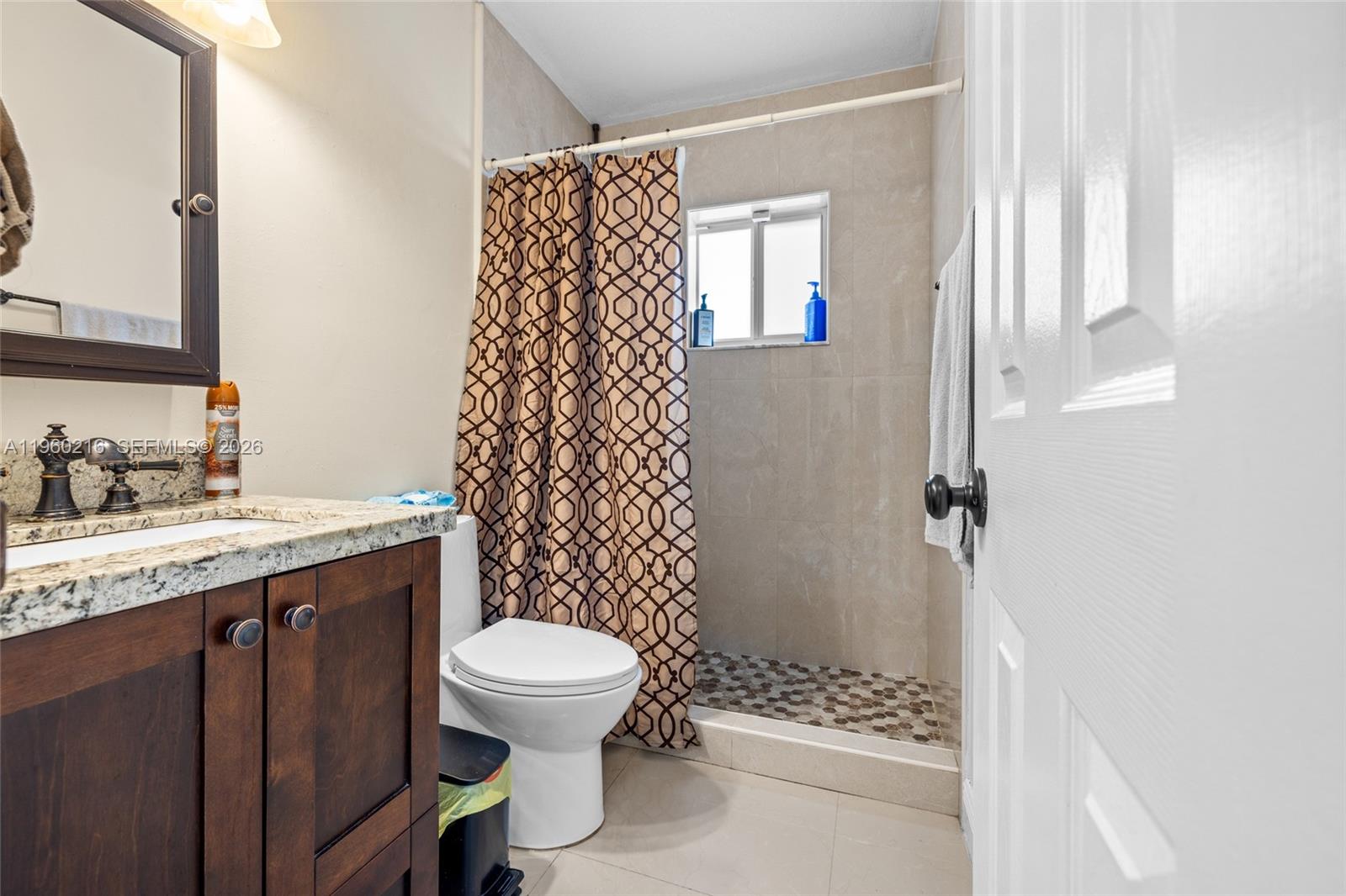 A bathroom features a dark wood vanity, granite countertop, toilet, and a tiled walk-in shower — 20814 SW 126th Ct, Miami FL 33177, MIAMI, FL